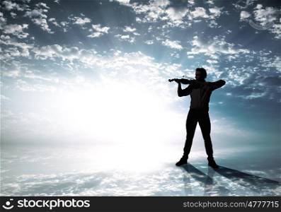 Man violinist. Silhouette of man playing violin high in sky