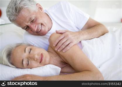 Man waking woman lying in bed sleeping