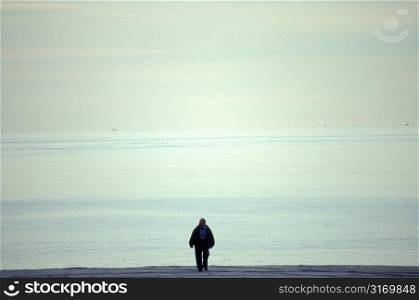 Man Walking Along An Empty Beach