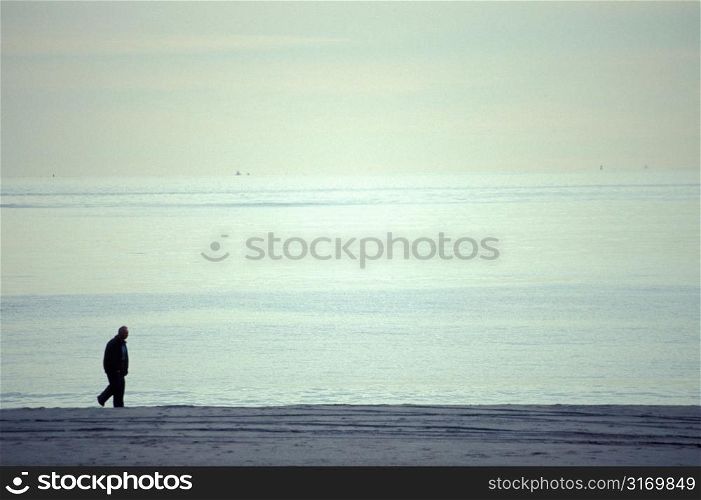 Man Walking Along An Empty Beach