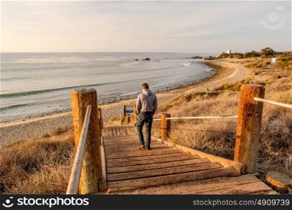 Man walking at boardwalk to Leo Carrillo State Beach, Malibu, California.