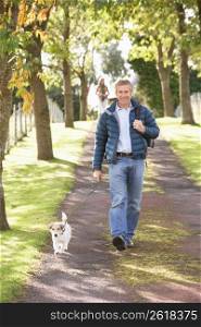 Man Walking Dog Outdoors In Autumn Park