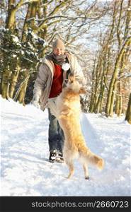 Man Walking Dog Through Snowy Woodland
