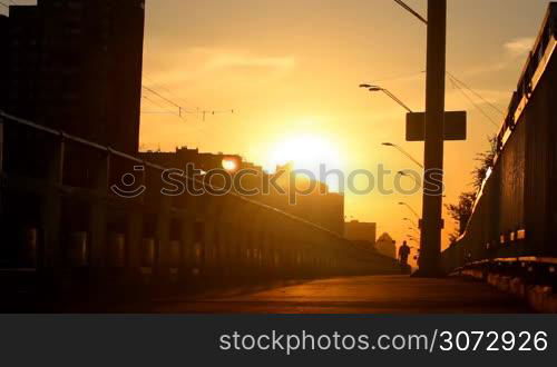 man walking on a bridge at sunset