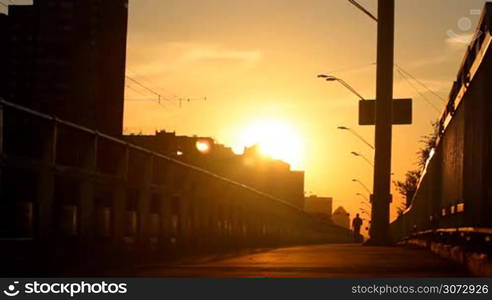 man walking on a bridge at sunset