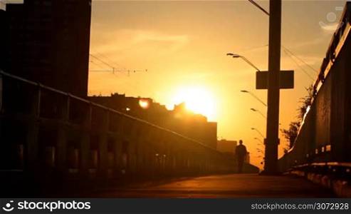 man walking on a bridge at sunset