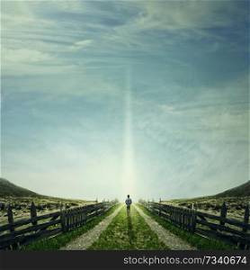 Man walking on a country road with a relax mood, following a light. Way of life concept