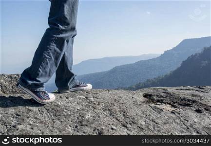 Man walking on edge of a cliff mountain top , travel concept