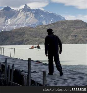 Man walking on jetty at Grey Lake, Torres del Paine National Park, Patagonia, Chile