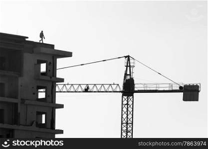 Man Walking on Roof of Contruction Site Building with Crane