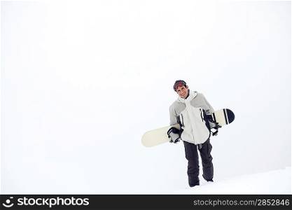 Man walking on snow carrying snowboard