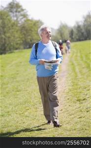 Man walking outdoors holding map smiling with people in background