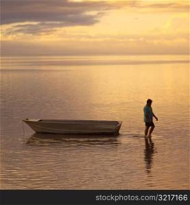 Man walking with boat in ocean at Moorea in Tahiti