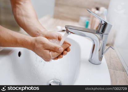 Man washes his face in bathroom, routine morning hygiene. Male person at the sink performs skin and body treatment procedures. Man washes his face in bathroom, morning hygiene