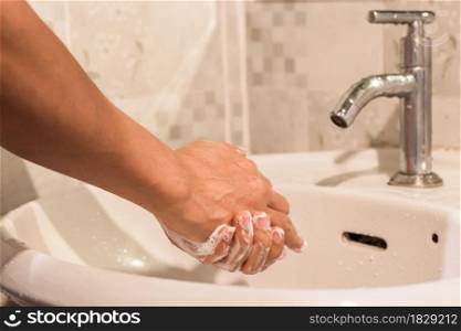 Man washes his hands with soap over a sink in the bathroom. Concept of hygiene treatment.