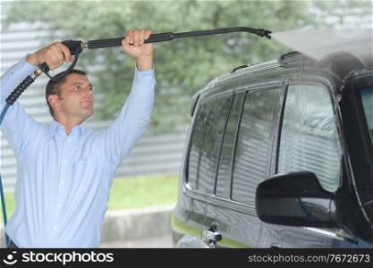 man washing car with high pressure spray