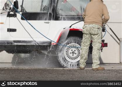 Man washing his car with a jet of water