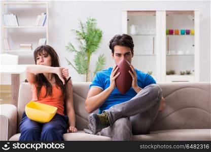 Man watching americal football with his wife