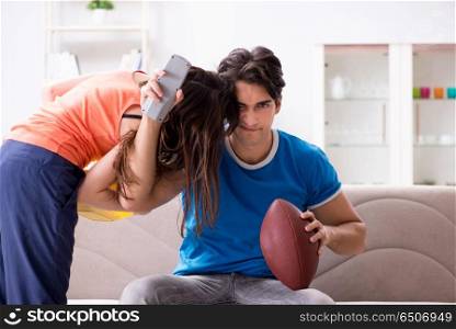 Man watching americal football with his wife