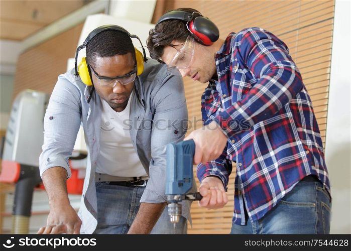 man watching mentor drill a wood board