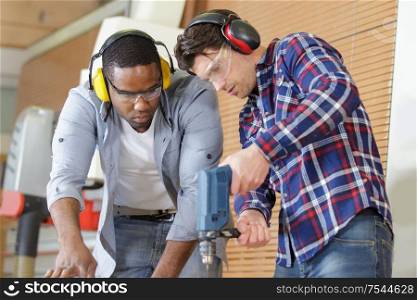 man watching mentor drill a wood board