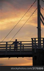 Man watching sunset on a footbridge in Perkins Cove, Maine