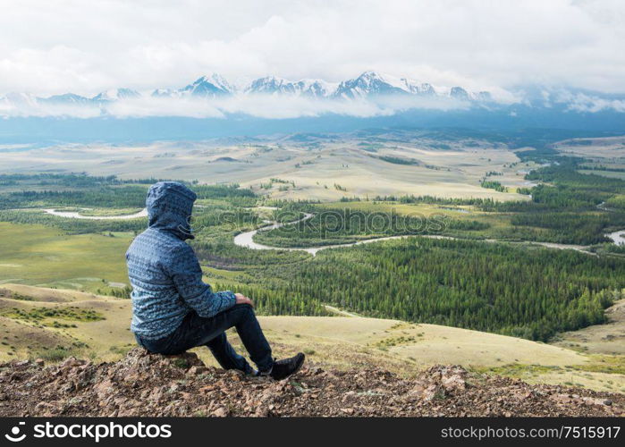 Man watching to glacier in Altai mountains. Resting in mountains or global warming concept. Relaxing man in Kurai steppe on North-Chui ridge