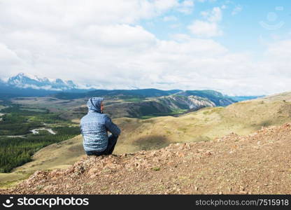 Man watching to glacier in Altai mountains. Resting in mountains or global warming concept. Relaxing man in Kurai steppe on North-Chui ridge