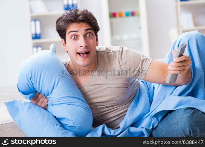 Man watching tv from bed holding remote control unit