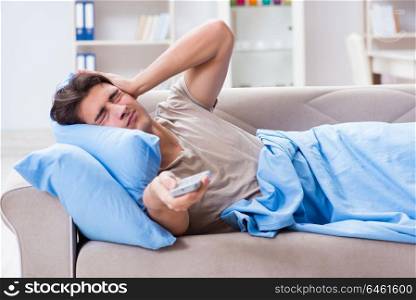 Man watching tv from bed holding remote control unit