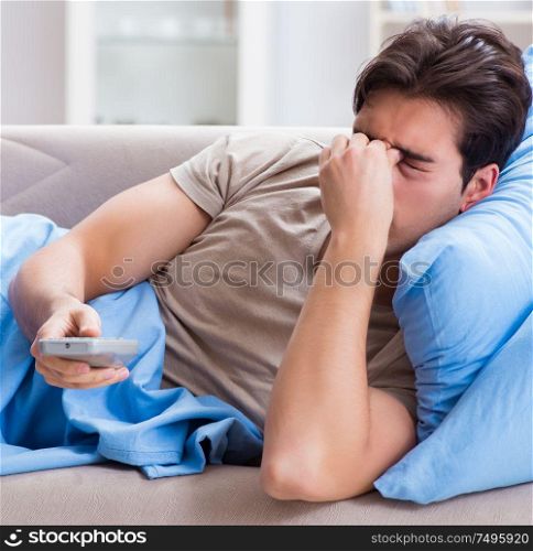 Man watching tv from bed holding remote control unit. The man watching tv from bed holding remote control unit