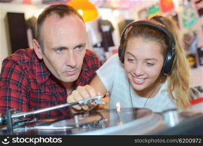 Man watching young lady putting vinyl record playing