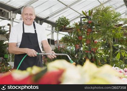 Man watering plants in a garden center