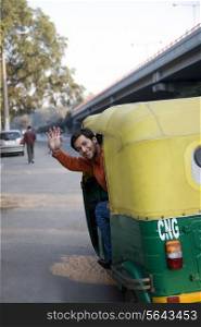 Man waving from an auto rickshaw