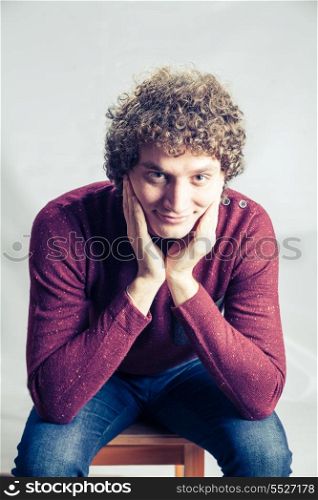 Man weared violet pullover. Curly white man in studio sitting