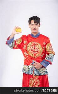 Man wearing a cheongsam holds a credit card to go shopping during the Chinese New Year.