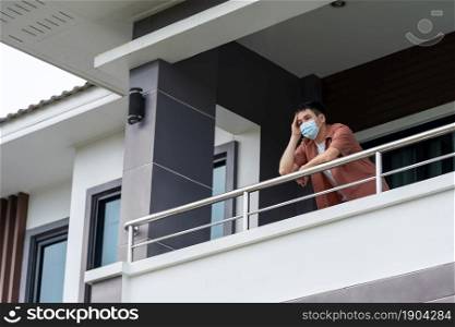 man wearing a face mask and quarantine in balcony of his home, coronavirus (covid-19) pandemic concept
