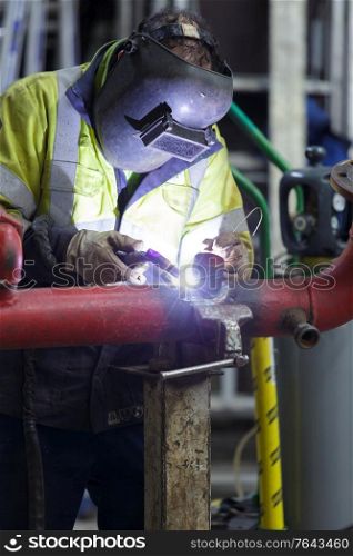 man wearing a mask welding pipes in industry