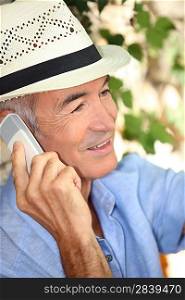 Man wearing a straw hat and talking on his mobile phone