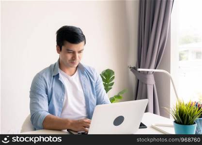 man wearing blue shirt as casual style and using laptop, working at home, technology aglie working home concept