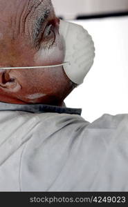 Man wearing face mask whilst sanding wall