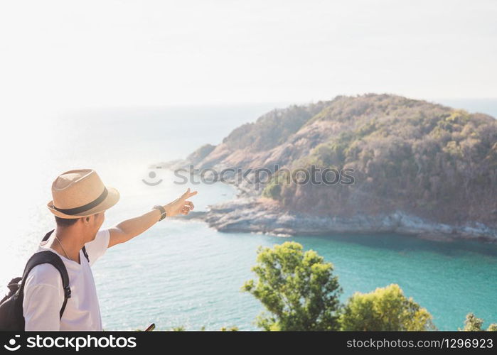 Man wearing hat holds his hand happy. Man asian tourist Look at mountains and the sea Before sunset.for activity lifestyle outdoors freedom or travel tourism inspiration backpacker tourist to covid 19