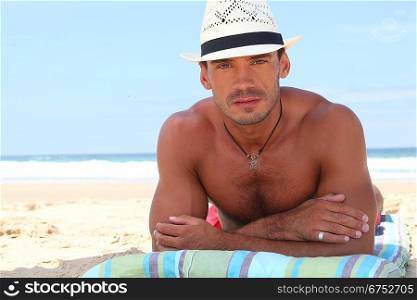 Man wearing hat sunbathing at beach