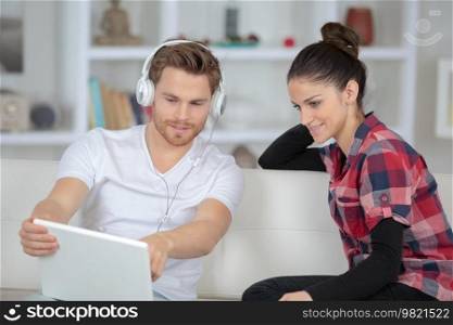 man wearing headphone pointing at the laptop
