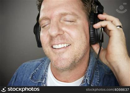 Man Wearing Headphones Enjoying His Music on a Grey Background.
