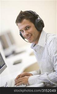Man wearing headphones in computer room typing and smiling
