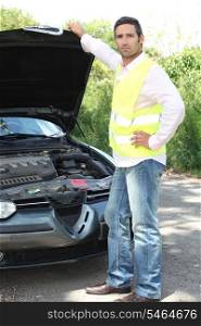 Man wearing high visibility jacket stood inspecting car engine