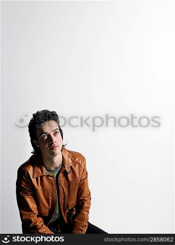 Man wearing leather coat sitting in studio