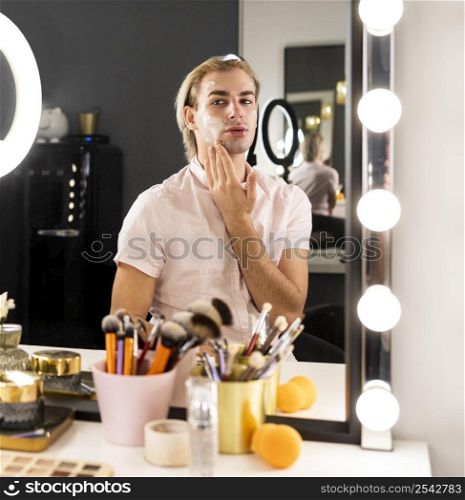 man wearing make up using face cream
