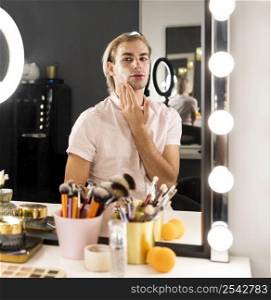 man wearing make up using face cream